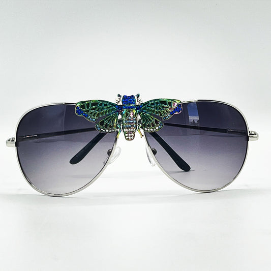 "Don't Bug Me" fashion eyewear by Orion Elise. Sleek silver frames with gradient blue and clear hues. Magnificent dragonfly embellishment symbolizes joy, happiness, and transformation. Embrace a journey of personal growth and enlightenment with "Don't Bug Me" eyewear. Alternatively, convey the sentiment of not wanting to be bothered. 